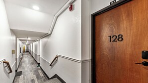 A hotel hallway with a wooden door labeled 128, a carpeted floor, and a handrail. - Cozy stay for 2: 5 Min Drive to Base,  Full Kitchen, Shared Hot Tub & Pool, Restaurants Nearby! (Park City)
