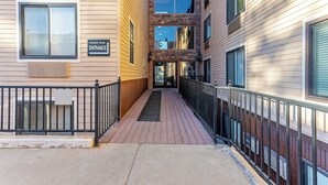 A corridor with a sign indicating the carriage house entrance, flanked by buildings with wooden siding and stone accents. - Cozy stay for 2: 5 Min Drive to Base,  Full Kitchen, Shared Hot Tub & Pool, Restaurants Nearby! (Park City)