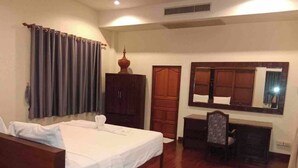 A hotel room with a bed, a desk, a chair, a wardrobe, and a mirror. - Nakara Samui-2 bedrooms Ocean View (Ko Samui District)
