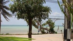 A coastal road with a palm tree and a concrete structure. - Nakara Samui-2 bedrooms Ocean View (Ko Samui District)