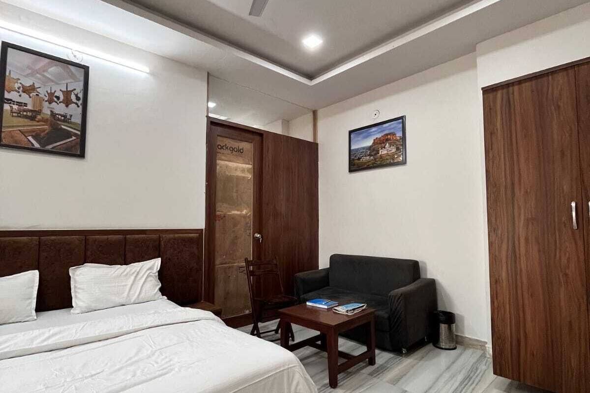 A hotel room with a bed, a chair, a table, a wardrobe, and a ceiling fan.