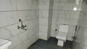A bathroom with white marble tiles, a white sink, a toilet, and a shower. - Hotel Raj Villas Palace (Jodhpur)