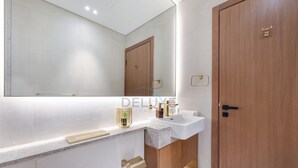 Een moderne badkamer met een grote spiegel, een houten deur en een wit wastafelmeubel.