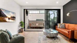 A modern living room with a sofa, armchair, and a coffee table. - Chic Home with BBQ & Outdoor Dining (Carnegie)