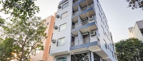 A multi-story building with balconies, air conditioning units, and a sign indicating it is a hotel.