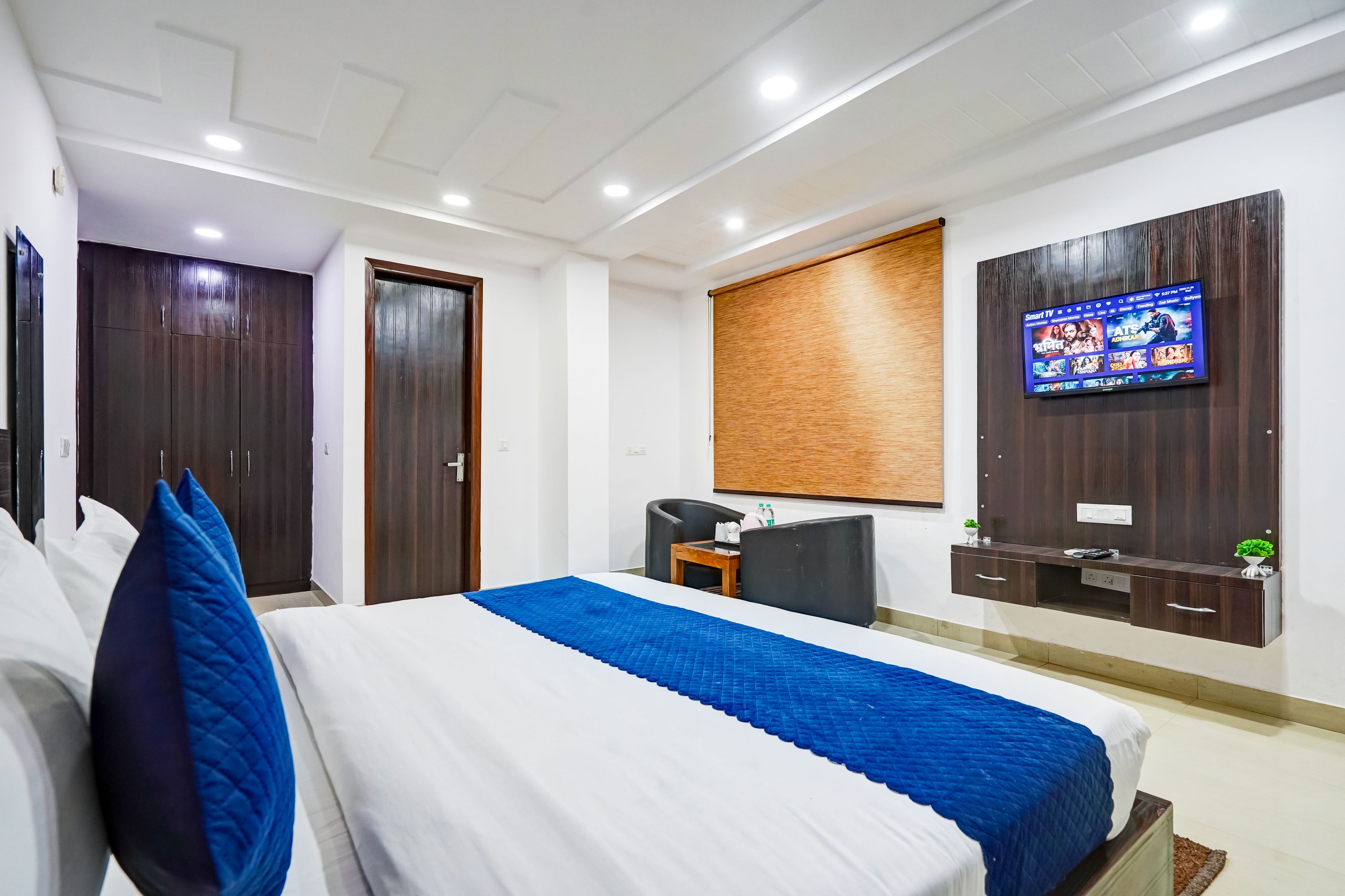 Una habitación de hotel con una cama, un escritorio, un televisor y un armario.