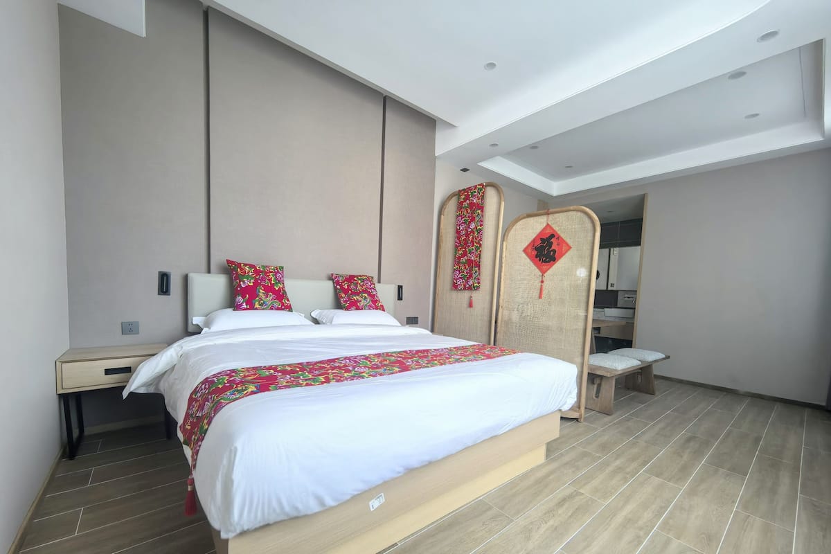 Habitación de hotel moderna con una cama grande, una mesita de noche, un armario y un pequeño banco.