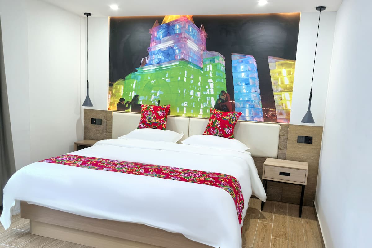 Una habitación de hotel moderna con una cama grande, dos mesitas de noche y un mural de un paisaje urbano colorido en la pared.