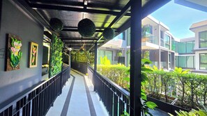 A covered corridor with a railing, green plants, and framed artwork. - Silk Ao Nang Condominium (Krabi)