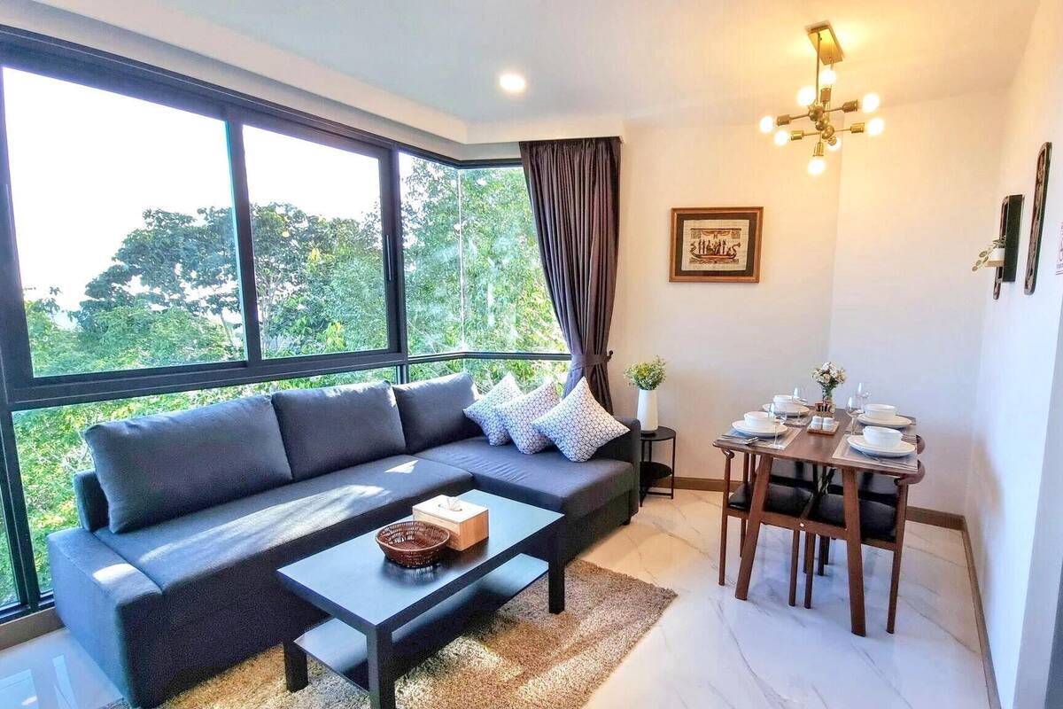 A modern living room with a sofa, coffee table, and dining table set for four.