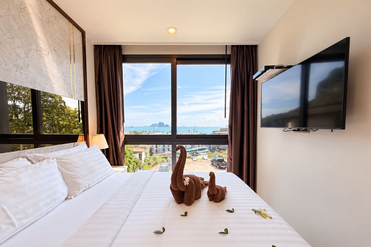 Una habitación de hotel con cama, televisión y vista al mar.