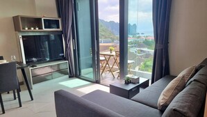 A modern living room with a sofa, a TV, and a dining area with a table and chairs. - Silk Ao Nang Condominium (Krabi)