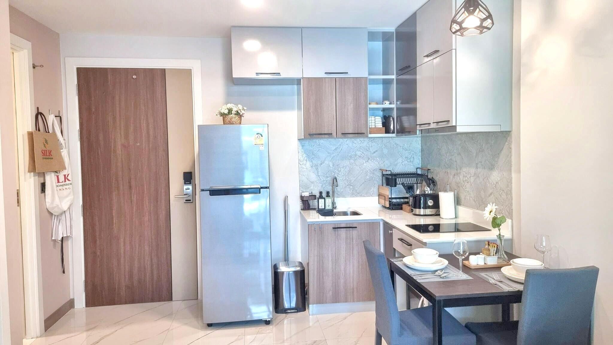A compact kitchen with a refrigerator, sink, and dining area.