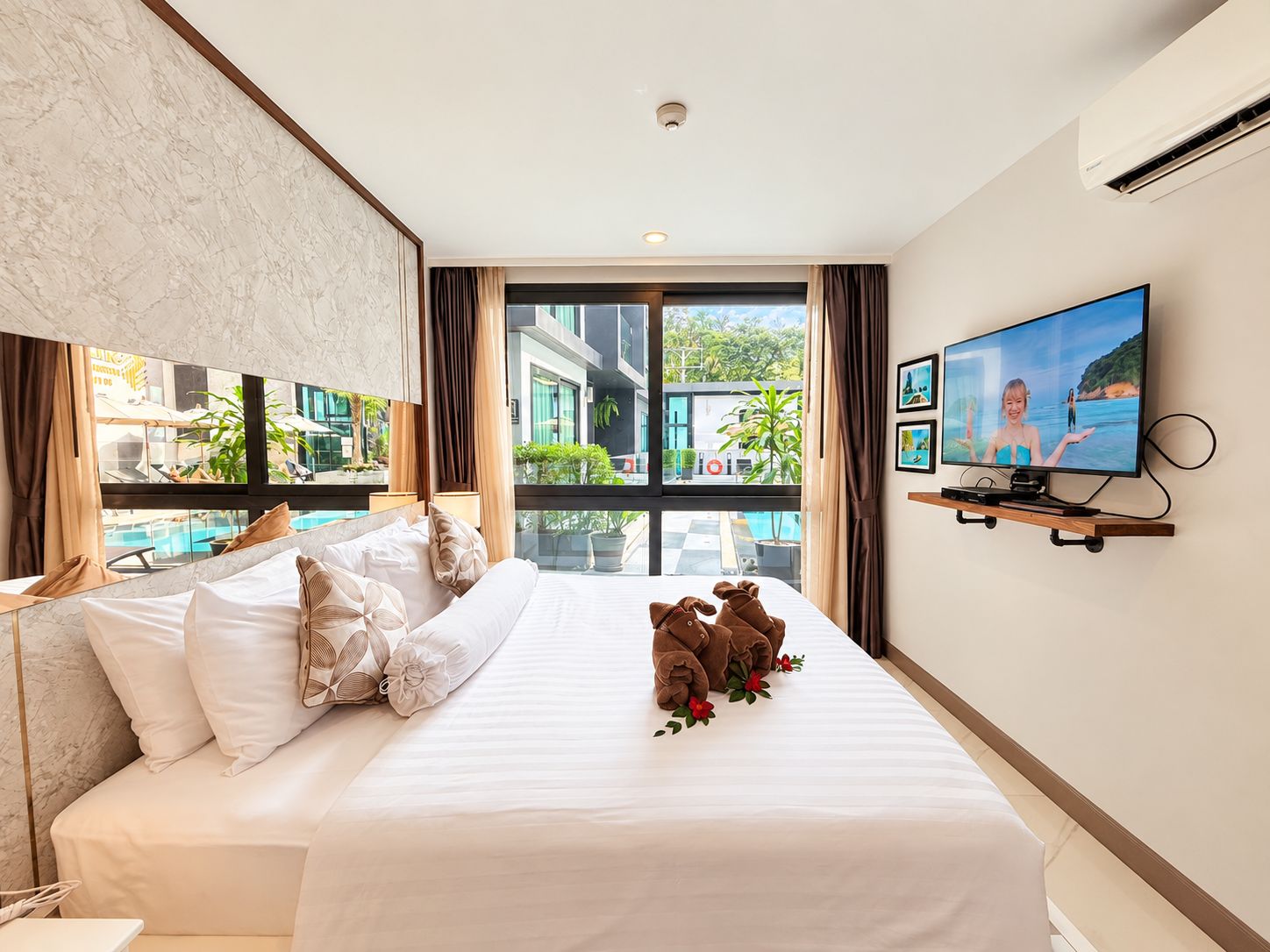 Ein Hotelzimmer mit einem Bett, einem Fernseher und Blick auf einen Pool sowie Gebäude.