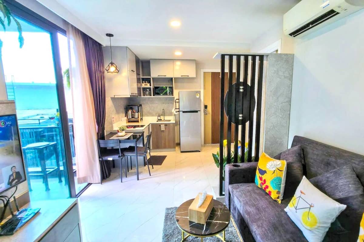 A modern living room with a sofa, a TV, and a dining area with a table and chairs.