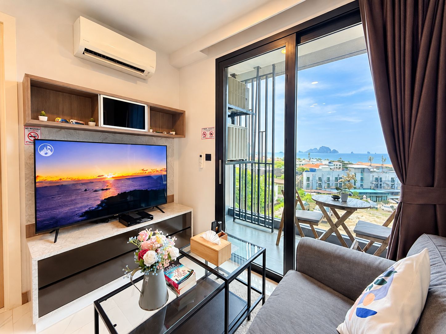 Uma sala de estar moderna com televisão de tela plana, uma mesa de centro com um vaso e um sofá.