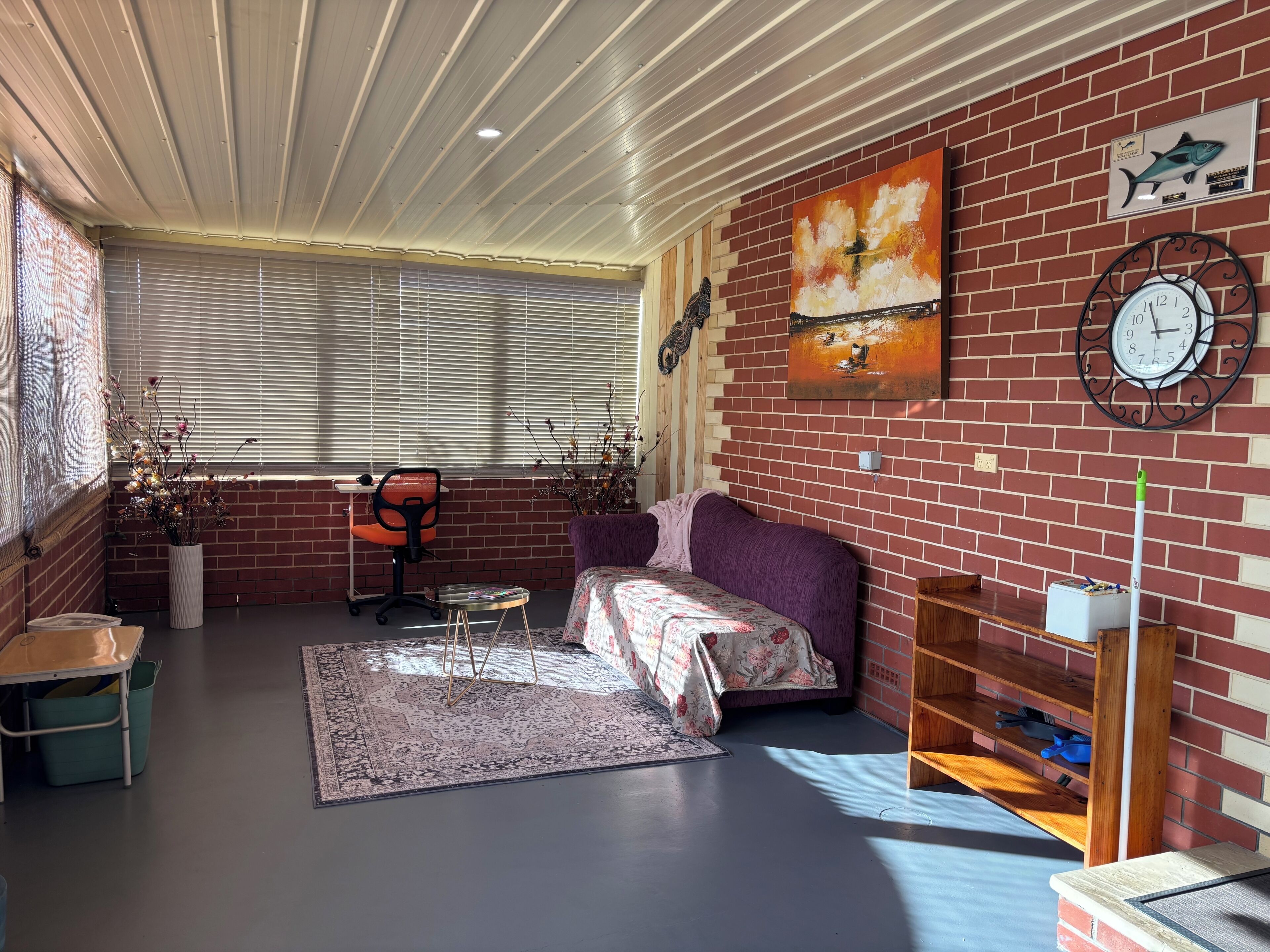 Ein Zimmer mit Ziegelwand, einer Couch, einem Sessel, einem kleinen Tisch und einer Uhr.
