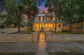A two-story house with a front porch, a gated entrance, and a well-maintained lawn. - Secret Garden Hideaway l Walk to DNTN l Sleeps 8 (St. Augustine)