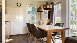 Een moderne keuken met witte tegels, een houten eettafel en bruine stoelen.