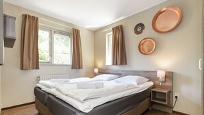 Een slaapkamer met een bed, twee nachtkastjes, een raam en gordijnen.