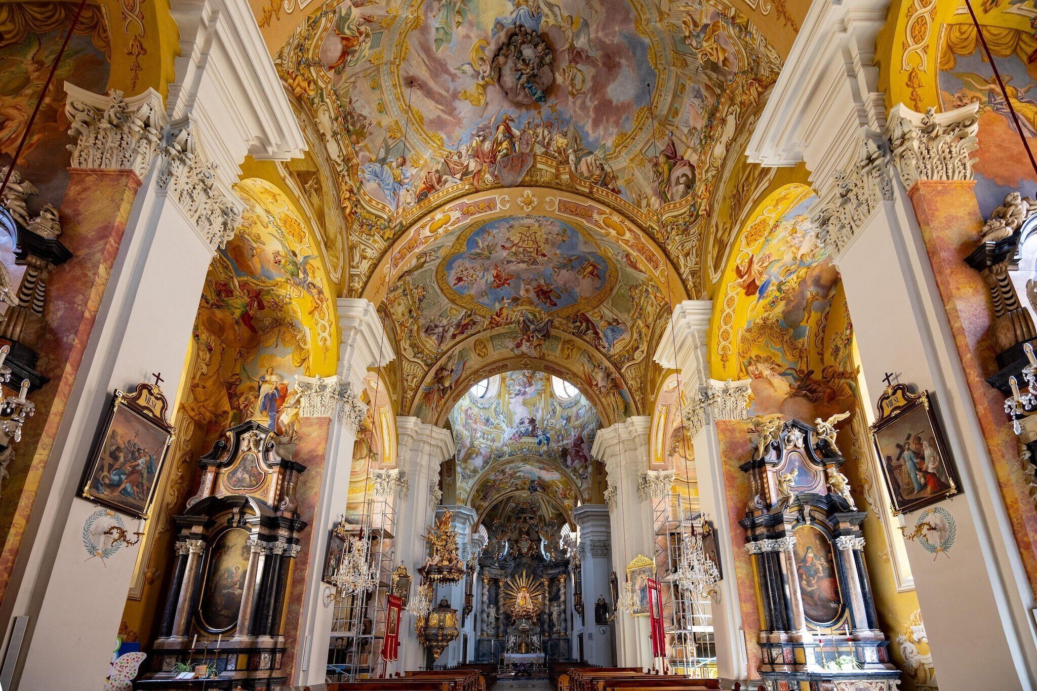 L’intérieur d’une église richement décorée, avec un autel central, de hauts plafonds et des œuvres d’art élaborées qui ornent le plafond.