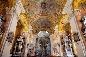 An ornate church interior with a central altar, high ceilings, and elaborate ceiling artwork. - Arcadio Home - Junior Suite (Graz)
