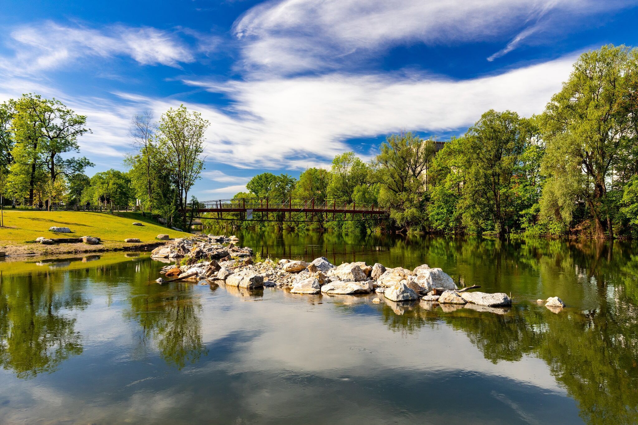 Un paysage paisible au bord de la rivière, avec un pont, des rochers et des arbres.