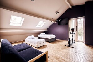 Ein Schlafzimmer im Loft-Stil mit zwei Betten, einem Schlafsofa, einem Deckenventilator, einem Fernseher und einem Fenster mit Blick.