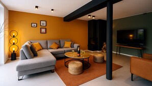 A modern living room with a grey sectional sofa, a round coffee table, and a flat-screen TV.