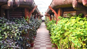 A corridor lined with potted plants and wooden buildings with checkered flooring. -  ECKO Beach Front, Puri (Puri)
