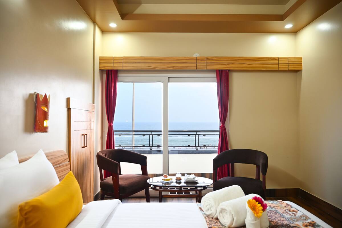 Ein Hotelzimmer mit Bett, zwei Stühlen, einem Tisch mit Frühstück und Meerblick.