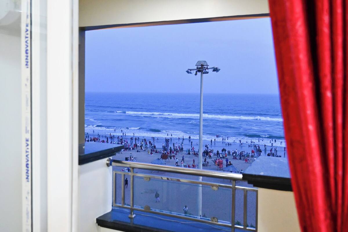 Ein Zimmer mit einem großen Fenster mit Blick auf einen Strand.