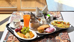 A breakfast tray with fruits, pastries, and juice on a table by a window overlooking a beach. -  ECKO Beach Front, Puri (Puri)