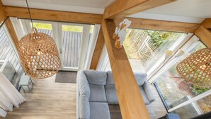 Et moderne interiør med træloft, en grå sofa og en hængende vævet lampe.