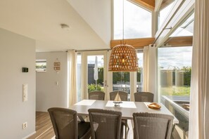 Un espace repas comprenant une table, des chaises et un luminaire suspendu.