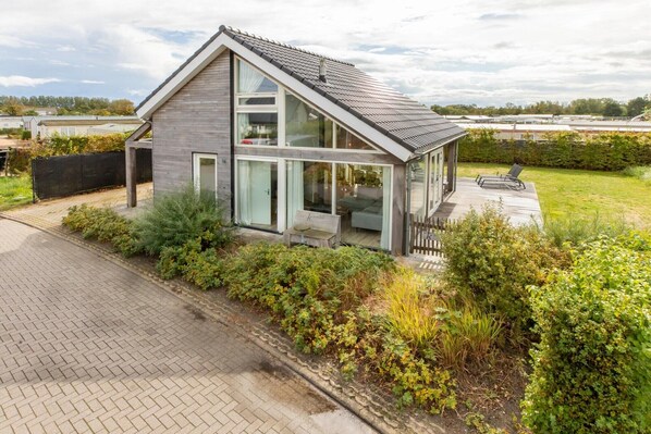 A modern two-story house with a sloped roof, large windows, and a well-maintained garden.