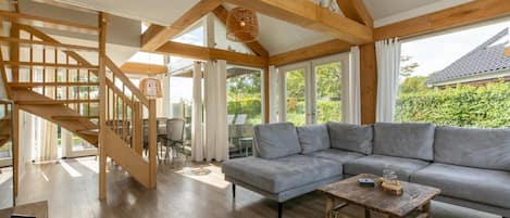 A spacious living area with a wooden staircase, a grey sofa, and a wooden coffee table.