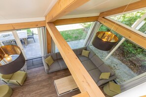 Un intérieur moderne avec un grand canapé, des lampes suspendues et une vue sur l’extérieur.