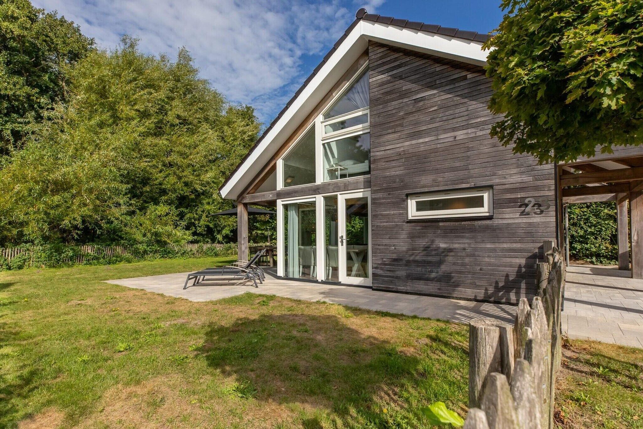 A modern two-story house with a large glass window, a wooden deck, and a number '23' on the side.