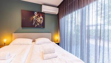 Een hotelkamer met een bed, twee bedlampen, een schilderij aan de muur en een raam met gordijnen.