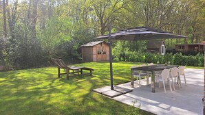 Un patio con mesa y sillas, un banco de madera y una estructura de pérgola.