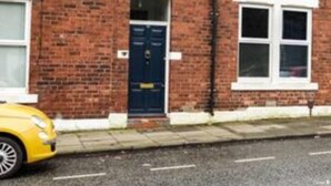 A two-story brick house with a blue door, white-framed windows, and a visible garage door. - Stags Hens Contractors Longstay (Newcastle-upon-Tyne)