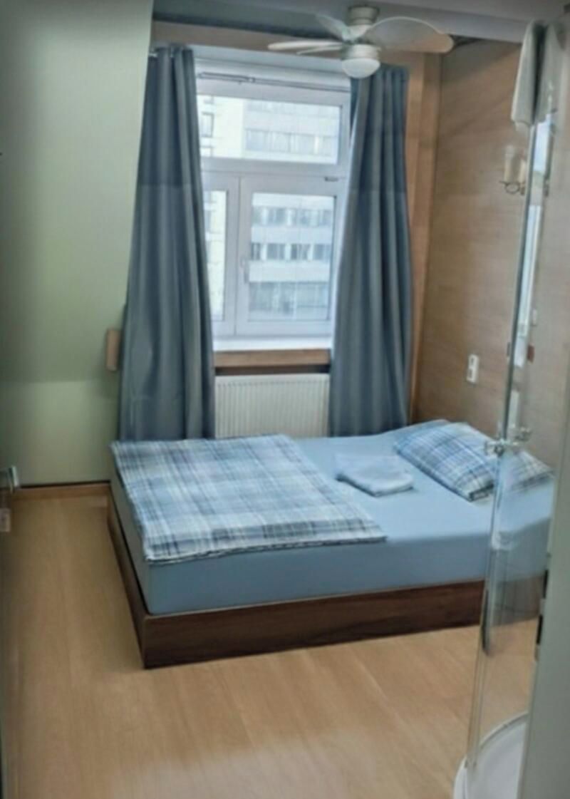 A bedroom with a bed, a window with curtains, and a ceiling fan.