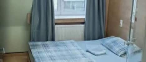 Ein Schlafzimmer mit Bett, einem Fenster mit Vorhängen und einem Deckenventilator.