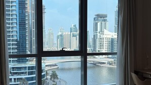 A modern hotel room with a large window offering a view of a city skyline and a river.