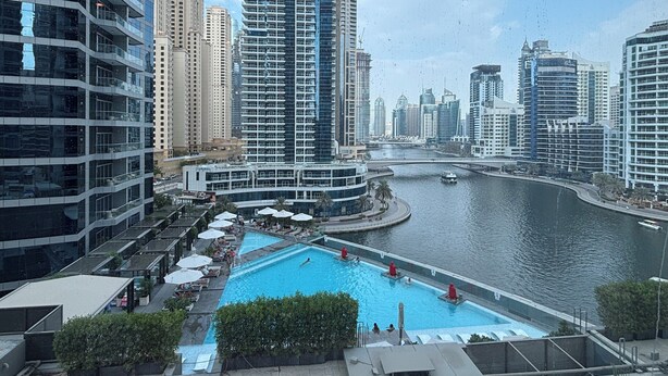 A high-rise building with a swimming pool and a river in the background.