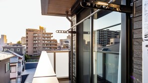 Un balcon donnant sur les bâtiments environnants, une porte vitrée et une rambarde en métal.