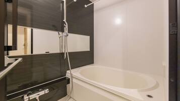 Un baño moderno con una bañera grande, un cabezal de ducha y un espejo.
