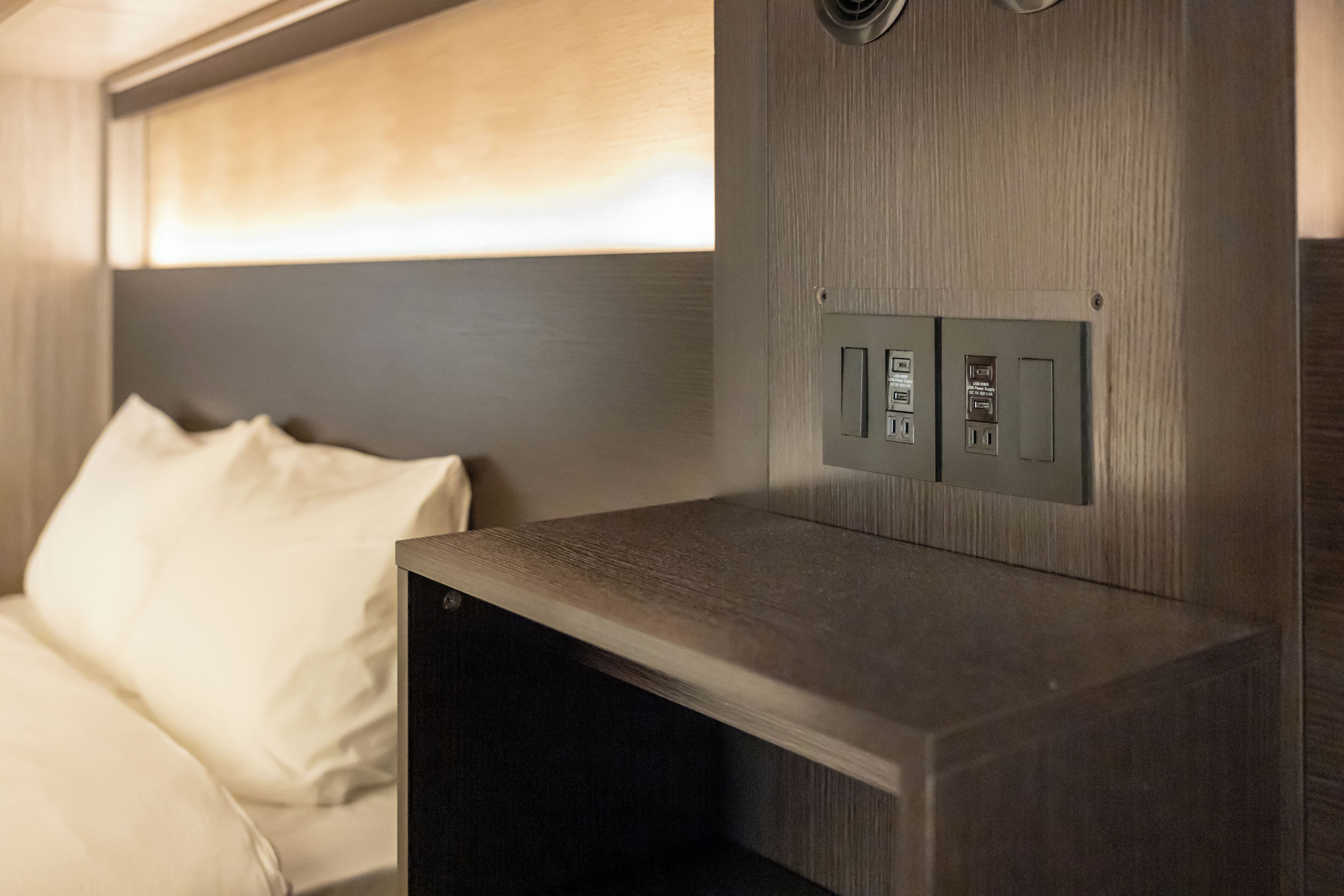 A modern bed with a headboard, a bedside table, and a control panel with buttons.