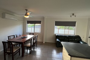 A dining area with a table and chairs, a ceiling fan, and two windows with blinds.